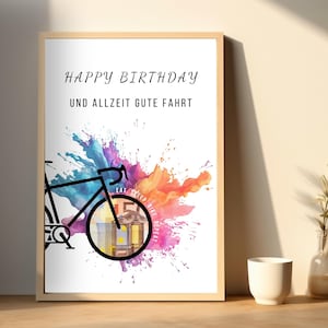 Geldgeschenk Fahrrad Geburtstag in einem Holzbilderrahmen auf dem Boden vor einer beigen Wand neben einer weißen Vase und einer Glasvase mit einem grünen Zweig darin.