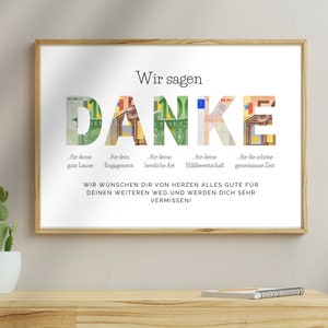 Abschiedsgeschenk Kollegin in einem Holzbilderrahmen an einer Wand über einen hölzernen Sideboard mit einem Kaktus und einem Notizbuch darauf