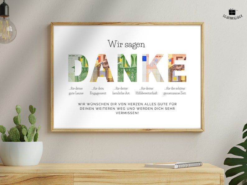 Abschiedsgeschenk Kollegin in einem Holzbilderrahmen an einer Wand über einen hölzernen Sideboard mit einem Kaktus und einem Notizbuch darauf