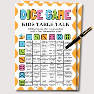 May include: A colorful "Dice Game Kids Table Talk" card with a bee illustration and dice graphics. The card features prompts for conversation starters. A black pen rests on the card, ready to play.