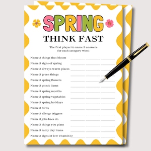 May include: A white game card with a yellow border and the text "SPRING THINK FAST". The card includes categories like "things that bloom" and "spring flowers". A black pen with gold accents rests on the card.