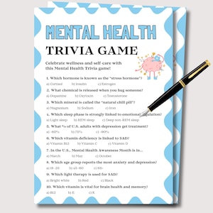 Pode incluir: Um cartão de jogo de perguntas e respostas sobre saúde mental com um design azul e branco, com perguntas sobre saúde mental. Uma caneta preta com detalhes dourados está sobre o cartão. O cartão inclui o texto "MENTAL HEALTH TRIVIA GAME".