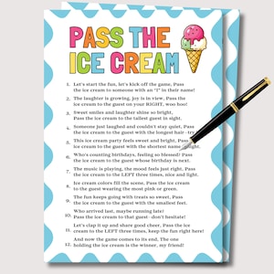 以下が含まれることがあります： 「Pass the Ice Cream」というタイトルのパーティーゲームカード。カラフルなテキストとアイスクリームコーンのイラストが描かれています。 金色のアクセントが付いた黒いペンがカードの上に置かれており、カードには水色の波状のボーダーがあります。