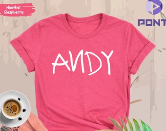 May include: A pink heather raspberry t-shirt with the word "ANDY" written in white on the front.