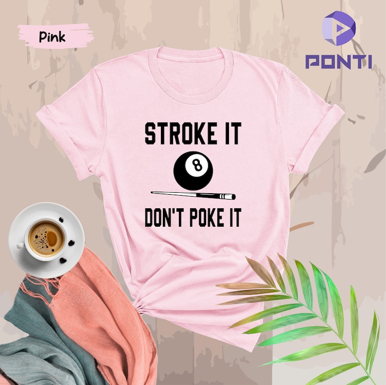 Op de afbeelding: Roze T-shirt met een zwarte afbeelding van een biljartstok en een achtbal met de tekst "STROKE IT DON'T POKE IT"