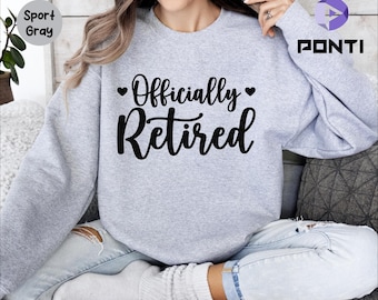 May include: A gray sweatshirt with the text "Officially Retired" in black lettering with a heart on either side of the word "Officially".