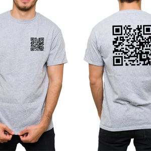 May include: Light gray t-shirt with a black QR code on the front left chest and a larger QR code on the back. The shirt is short-sleeved and made of a soft material. The QR codes are a prominent design element.