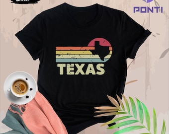May include: Black t-shirt with a vintage-style graphic of the state of Texas in a sunset color palette. The text "TEXAS" is printed below the graphic.
