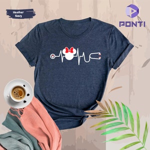 May include: A heather navy blue t-shirt featuring a white graphic of a stylised Mickey Mouse head with a red bow, a stethoscope, and a heartbeat line.