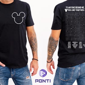 以下が含まれることがあります： 前面にミッキーマウスの頭の白いアウトラインが描かれた黒いTシャツ。背面にはディズニーをテーマにした単語検索とテキスト「TO ANYONE BEHIND ME, WE'RE IN THIS LINE TOGETHER. ENJOY!」が表示されています。