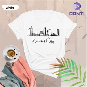 May include: White t-shirt with a black line drawing of the Kansas City skyline and the text "Kansas City" underneath.