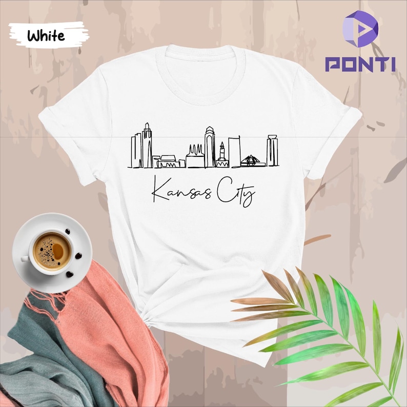 May include: White t-shirt with a black line drawing of the Kansas City skyline and the text "Kansas City" underneath.