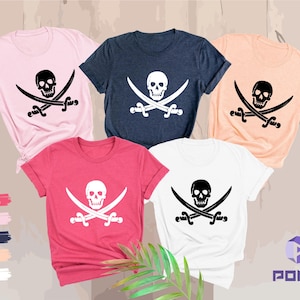 May include: Five short-sleeved t-shirts in various colors: pink, navy, peach, white, and red. Each shirt features a black skull and crossbones graphic. The shirts are displayed on a neutral background.