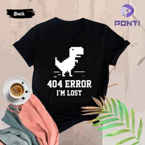 May include: Black t-shirt with a white pixelated dinosaur and the text "404 ERROR I'M LOST".