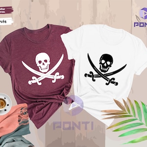 May include: Two t-shirts, one heather maroon and one white, each featuring a skull and crossed swords design. The white shirt has a black graphic, while the maroon shirt has a white graphic. The shirts are short-sleeved.