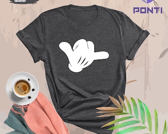 May include: Dark grey heather t-shirt featuring a white cartoon hand making a shaka sign. The shirt is a casual style with short sleeves and a crew neck.