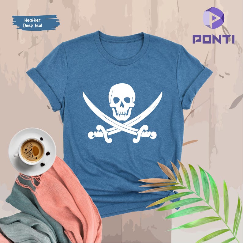 May include: Heather deep teal t-shirt featuring a white skull and crossbones graphic. The shirt has rolled-up sleeves and a crew neck. The text "Heather Deep Teal" is in a blue rectangle in the upper left corner. A cup of coffee and a scarf are in the lower left.