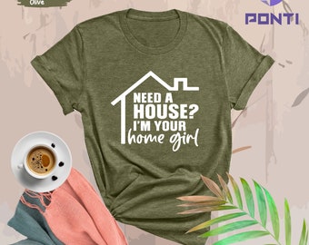 Op de afbeelding: Een heide-olijfkleurig T-shirt met de tekst "Need a house? I'm your home girl" in witte letters. De tekst staat in een witte omtrek van een huis.