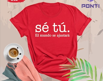May include: Red t-shirt with white text that reads "sé tú. El mundo se ajustará".