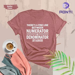 May include: A heather mauve t-shirt with the text "THERE'S A FINE LINE BETWEEN NUMERATOR & DENOMINATOR *ONLY A FRACTION WILL UNDERSTAND".