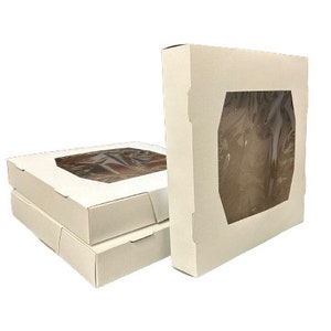 Puede incluir: Tres cajas de cartón blancas con ventanas de plástico transparente. Las cajas están apiladas una encima de la otra. Las cajas están diseñadas para empaquetar y exhibir artículos.