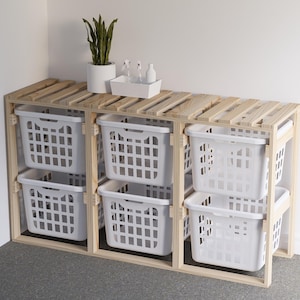 May include: A wooden laundry storage unit with six white plastic baskets. The unit has three shelves and is made of natural wood.