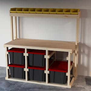 Op de afbeelding: Een houten werkbank met een plank erboven voor opslag. De plank heeft gele plastic bakken. De werkbank heeft een houten blad en een frame met zwarte plastic bakken eronder.