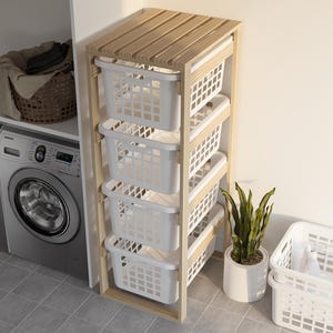 May include: A wooden laundry sorter with four white plastic baskets. The sorter has a natural wood finish and is placed next to a washing machine and a potted plant. A separate white basket is on the floor.