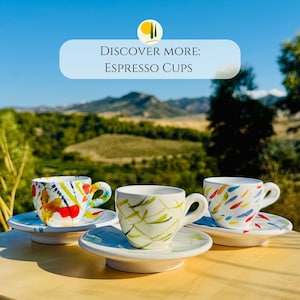 May include: Three white ceramic espresso cups with matching saucers, each featuring distinct hand-painted colourful patterns including abstract red, yellow, and blue brushstrokes. The text DISCOVER MORE: ESPRESSO CUPS is visible at the top of the image.