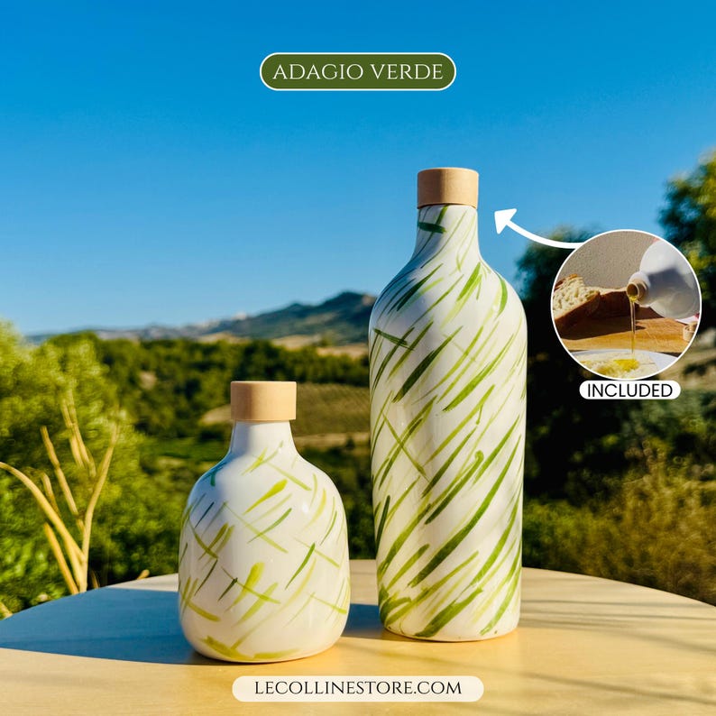 May include: Two white ceramic bottles with light green brushstroke patterns and light wood stoppers. The taller bottle is slender, while the shorter one is rounded. An inset shows oil pouring from a bottle onto bread with the text INCLUDED.