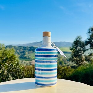 Handgefertigte Keramikflasche 500ml mit glatter weißer Oberfläche, verziert mit eleganten blauen Linien. Mittelgroß, perfekt für Öl oder Essig, verleiht Ihrer Küche einen mediterranen Touch. Die Textur ist glänzend und leicht zu handhaben.
