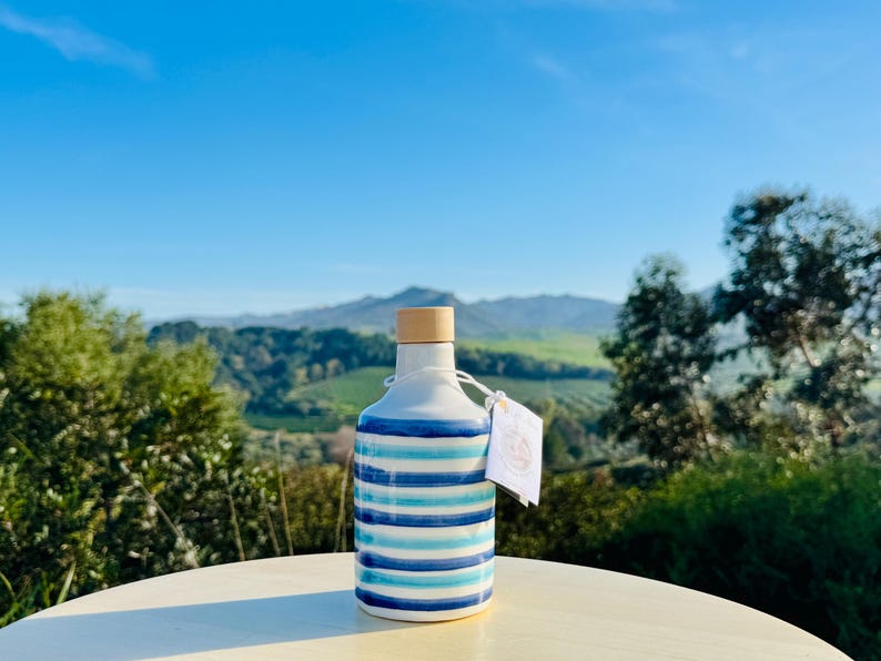 Handgefertigte Keramikflasche 250 ml mit glatter weißer Oberfläche, verziert mit eleganten blauen Linien. Klein, perfekt für Öl oder Essig, verleiht Ihrer Küche einen mediterranen Touch. Die Textur ist glänzend und leicht zu handhaben.