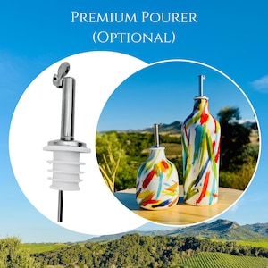 May include: A silver metal pourer with a white silicone stopper and two ceramic bottles featuring a multi-coloured paint stroke pattern. The text "PREMIUM POURER (OPTIONAL)" is displayed above the items, which are set against a blue sky.