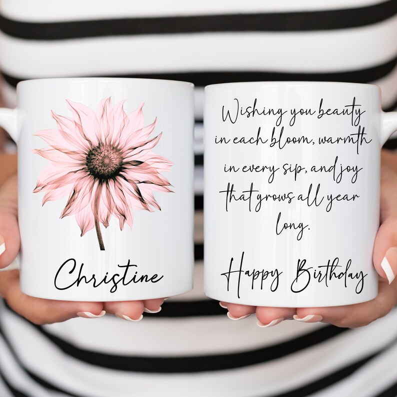 May include: White ceramic mug with a pink flower and the name "Christine". The other side of the mug has the text "Wishing you beauty in each bloom, warmth in every sip, and joy that grows all year long. Happy Birthday."
