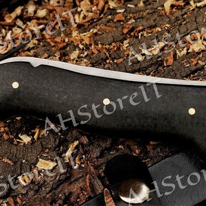 May include: A black and silver knife with a black handle and three brass accents. The handle is made of a textured material.