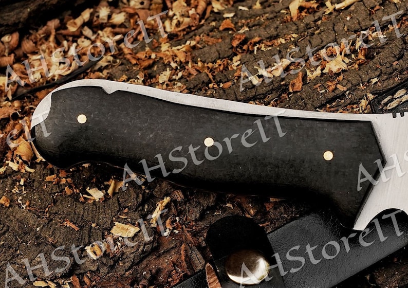 May include: A black and silver knife with a black handle and three brass accents. The handle is made of a textured material.