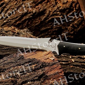 May include: A silver knife with a black handle and a wood grain pattern. The knife has a serrated edge and a pointed tip. The knife is resting on a piece of wood.