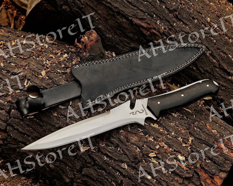 May include: A black leather sheath with a silver knife with a black wooden handle. The knife has a curved blade and the text "REMARK" is engraved on the blade.