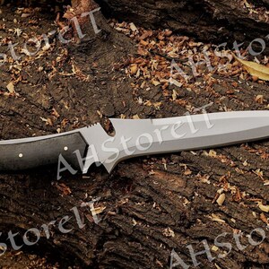 May include: A black-handled knife with a silver blade. The knife is lying on a brown, textured surface.