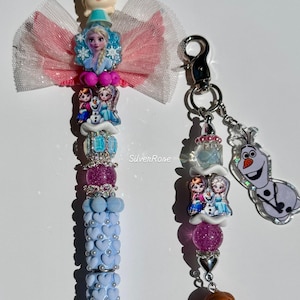 May include: A decorative pen and keychain set featuring characters from a popular animated film. The pen has a light blue barrel with heart-shaped accents and a bow. The keychain includes character charms and a silver clasp. The text "Silver Rose" is visible.
