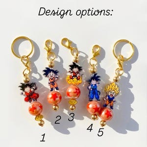 Puede incluir: Cinco llaveros de tono dorado numerados del 1 al 5, cada uno con un dije de acr&iacute;lico de personaje de anime, una cuenta naranja con estrellas rojas y cuentas doradas peque&ntilde;as. El texto "Design options:" aparece sobre los llaveros.
