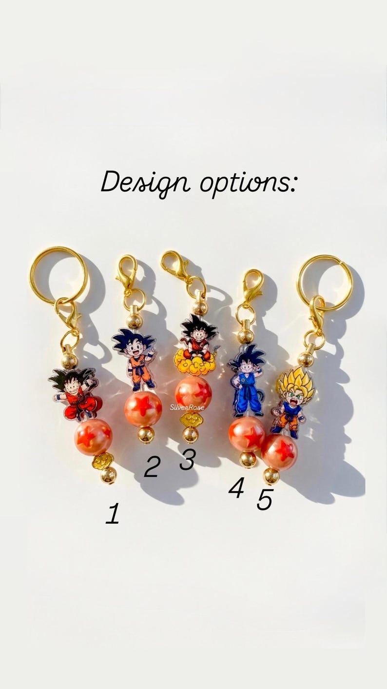 Puede incluir: Cinco llaveros de tono dorado numerados del 1 al 5, cada uno con un dije de acr&iacute;lico de personaje de anime, una cuenta naranja con estrellas rojas y cuentas doradas peque&ntilde;as. El texto "Design options:" aparece sobre los llaveros.
