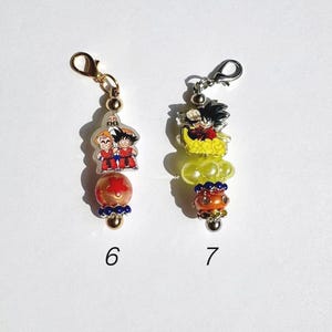 Puede incluir: Dos dijes decorativos etiquetados 6 y 7. El dije 6 tiene un broche de langosta dorado, una pieza acr&iacute;lica transparente con tres personajes, una cuenta naranja con una estrella roja y un acento azul. El 7 tiene un broche plateado, un personaje sobre una nube amarilla, una cuenta amarilla y una cuenta naranja con pedrer&iacute;a.