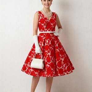 May include: A red floral print dress with a V-neck and a white belt. The dress has a flared skirt and is paired with white gloves, a white handbag, and white heels. A pearl necklace completes the look.