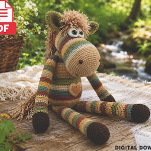 May include: A crocheted stuffed horse toy featuring horizontal stripes in shades of brown, green, tan, and cream. The horse has a textured mane, large white eyes with green pupils, and a tan heart-shaped patch on its chest. The limbs are long.