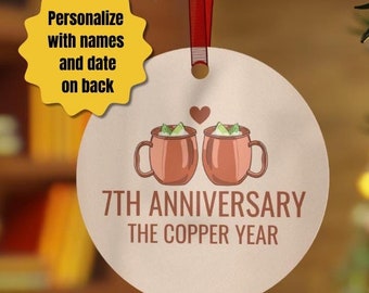 May include: A round, copper-colored ornament with a red ribbon for hanging. It features two mugs with a heart above them and the text "7th Anniversary The Copper Year." A yellow tag says "Personalize with names and date on back."