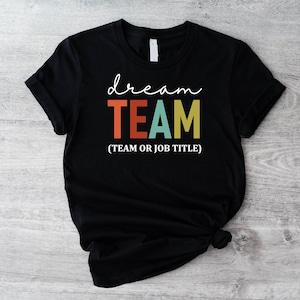 Op de afbeelding: Zwart T-shirt met de tekst "dream TEAM (TEAM OR JOB TITLE)" in kleurrijke letters.
