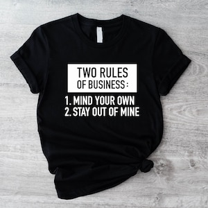 May include: Black t-shirt with white text that reads "TWO RULES OF BUSINESS: 1. MIND YOUR OWN 2. STAY OUT OF MINE"