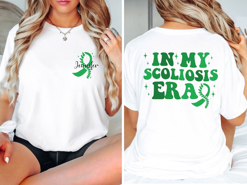 Pu&ograve; includere: Maglietta bianca con un nastro verde e il testo "Jennifer" sul davanti. La parte posteriore della maglietta ha il testo "In My Scoliosis Era" con un nastro verde.