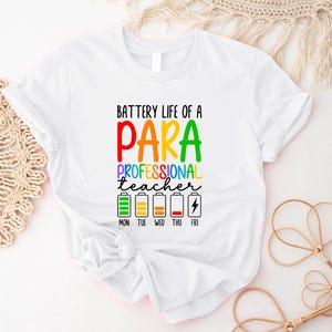 Könnte beinhalten: Weißes T-Shirt mit dem Text "BATTERY LIFE OF A PARA PROFESSIONAL TEACHER" in bunten Buchstaben. Darunter befinden sich Batteriestandsanzeigen für jeden Wochentag, von Montag bis Freitag.